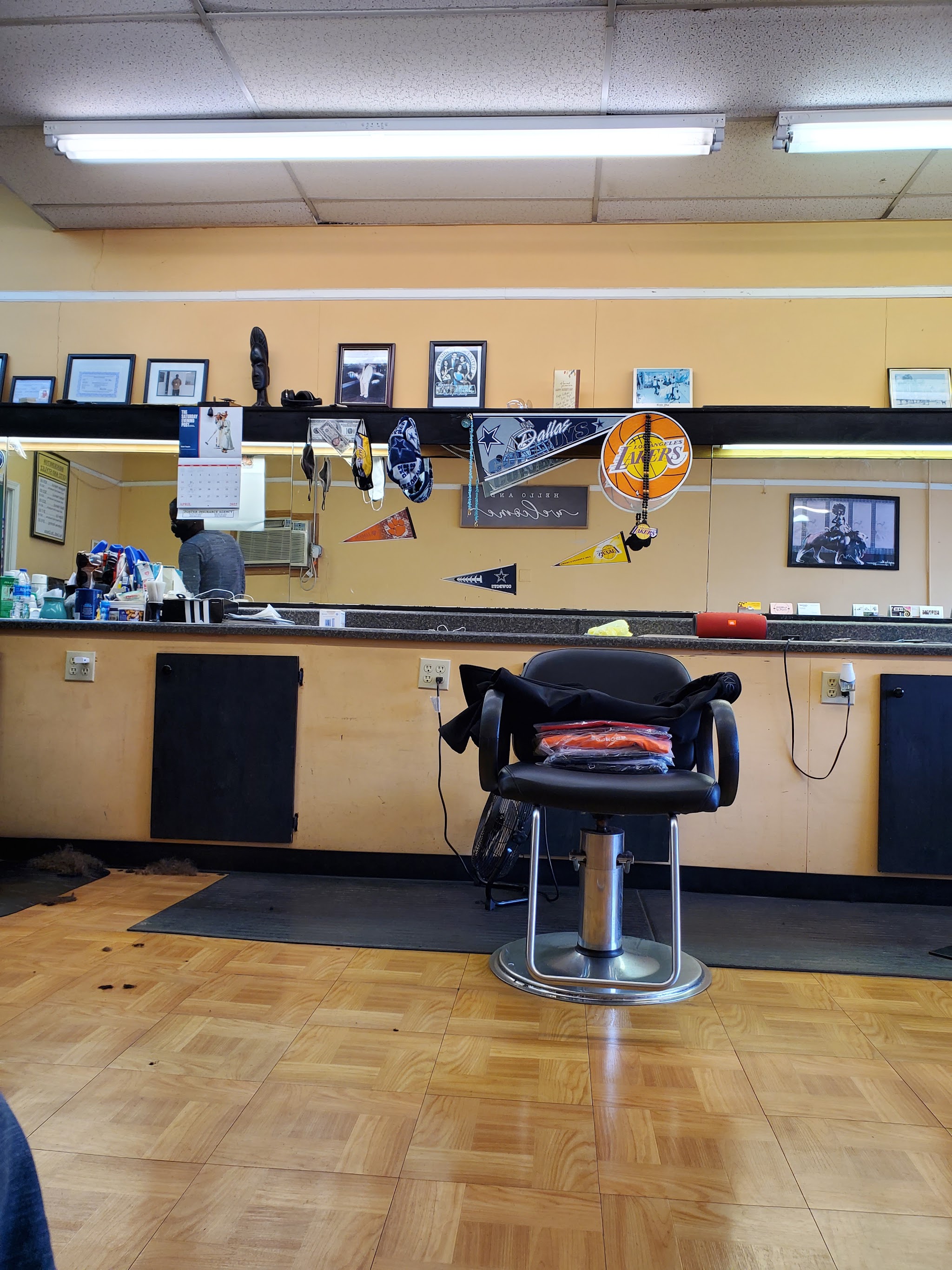 Inside the shop: a barber chair in front of the mirror wall with team pennants